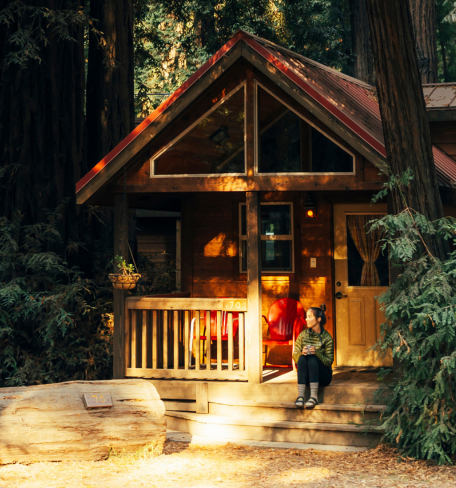 a woman sitting on a porch of a cabin in Big Sur