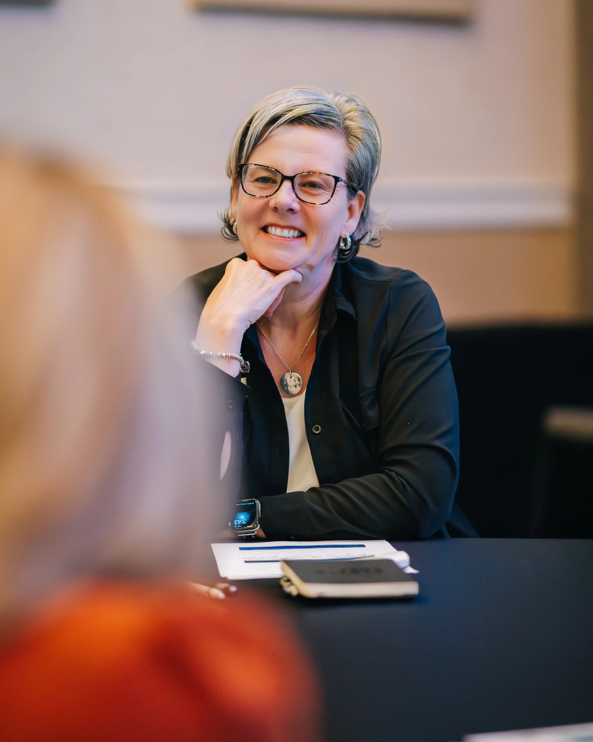 a woman sitting at a table smiling