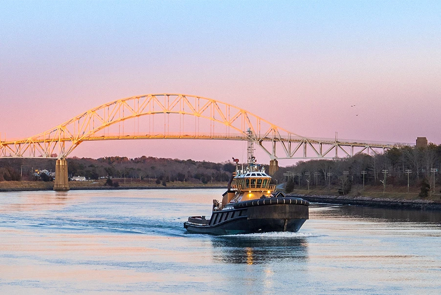 a boat sailing on a river with a bridge in the background