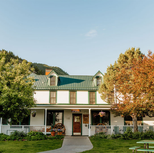 a house with a green roof and a white fence