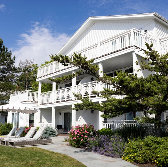 a white house with lawn chairs and trees