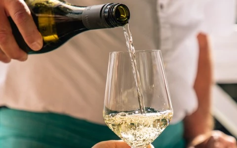 a person pouring a glass of wine