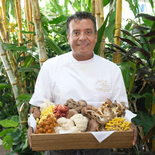 a man holding a wooden box of mushrooms
