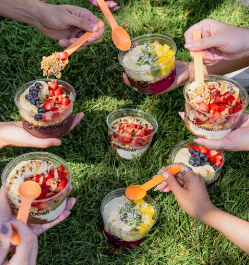 a group of hands holding cups of food