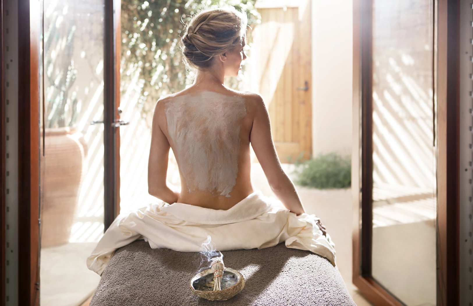 a woman sitting on a massage table with a white substance on her back