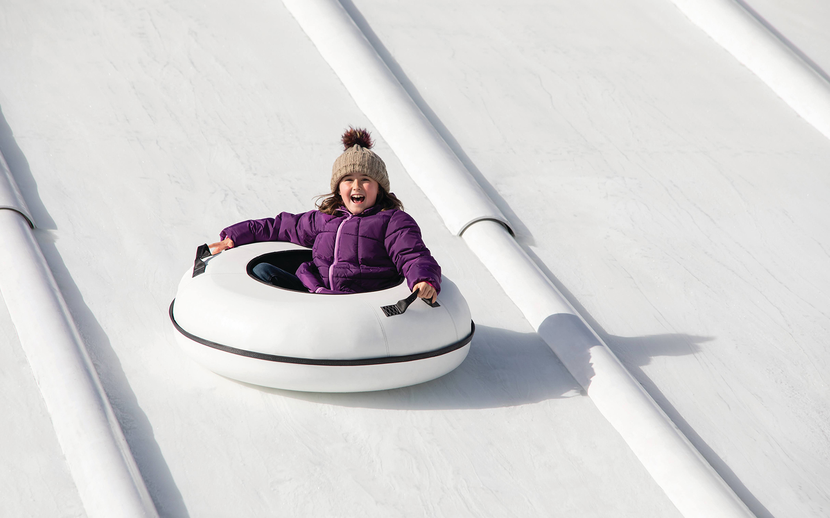 a smiling girl riding in a tube down the snow