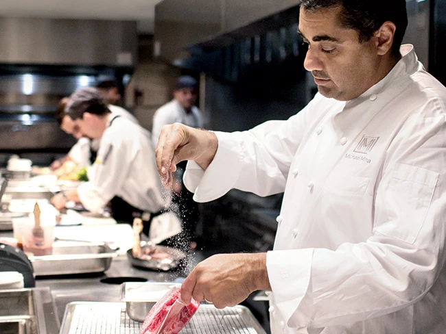 a chef putting salt on a piece of meat