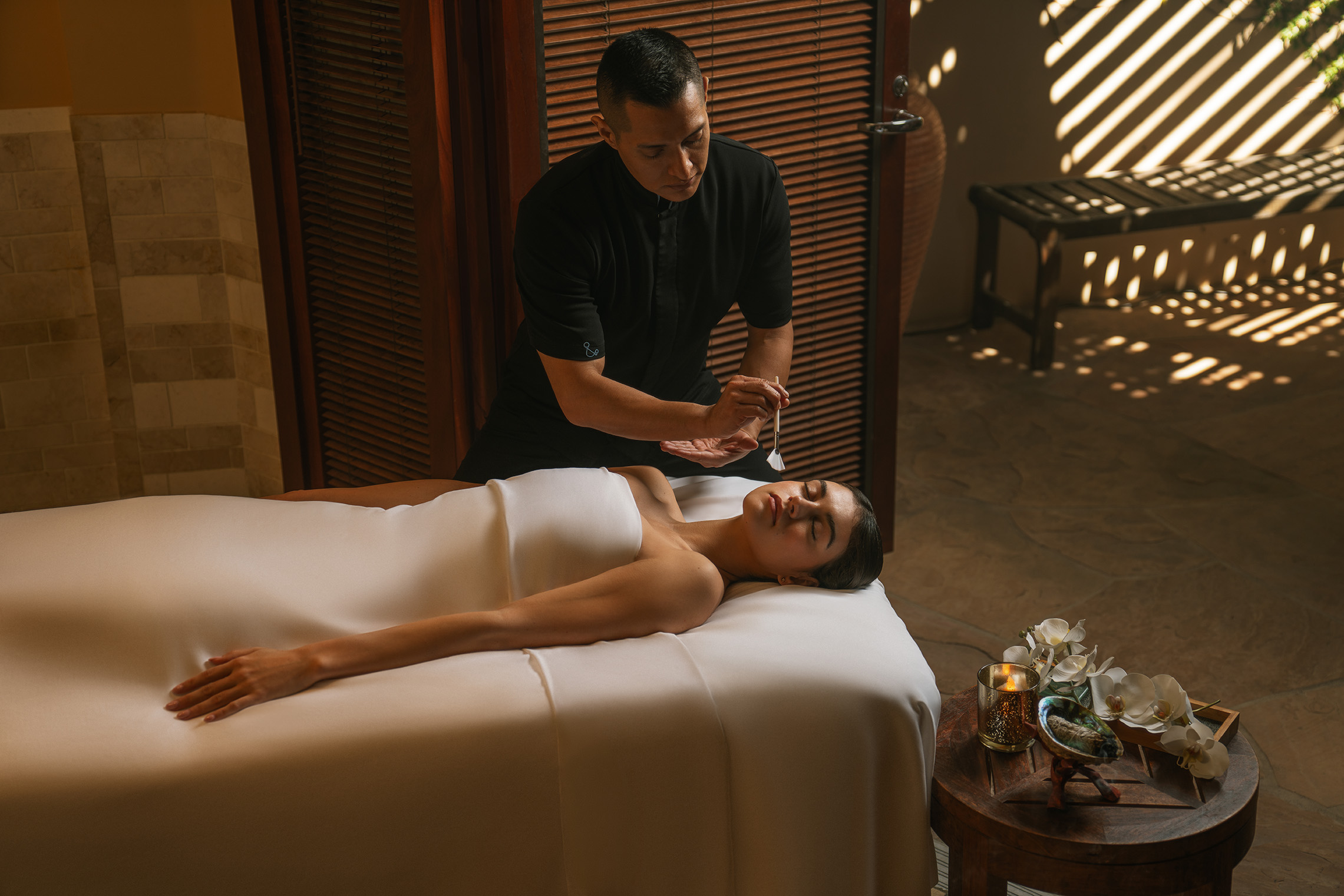 a man holding a stick to a woman lying on a bed