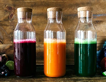 three bottles containing red, green, and orange liquid