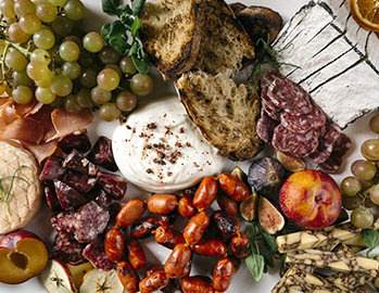 assortment of cheeses, meats, and fruits arranged on a table 