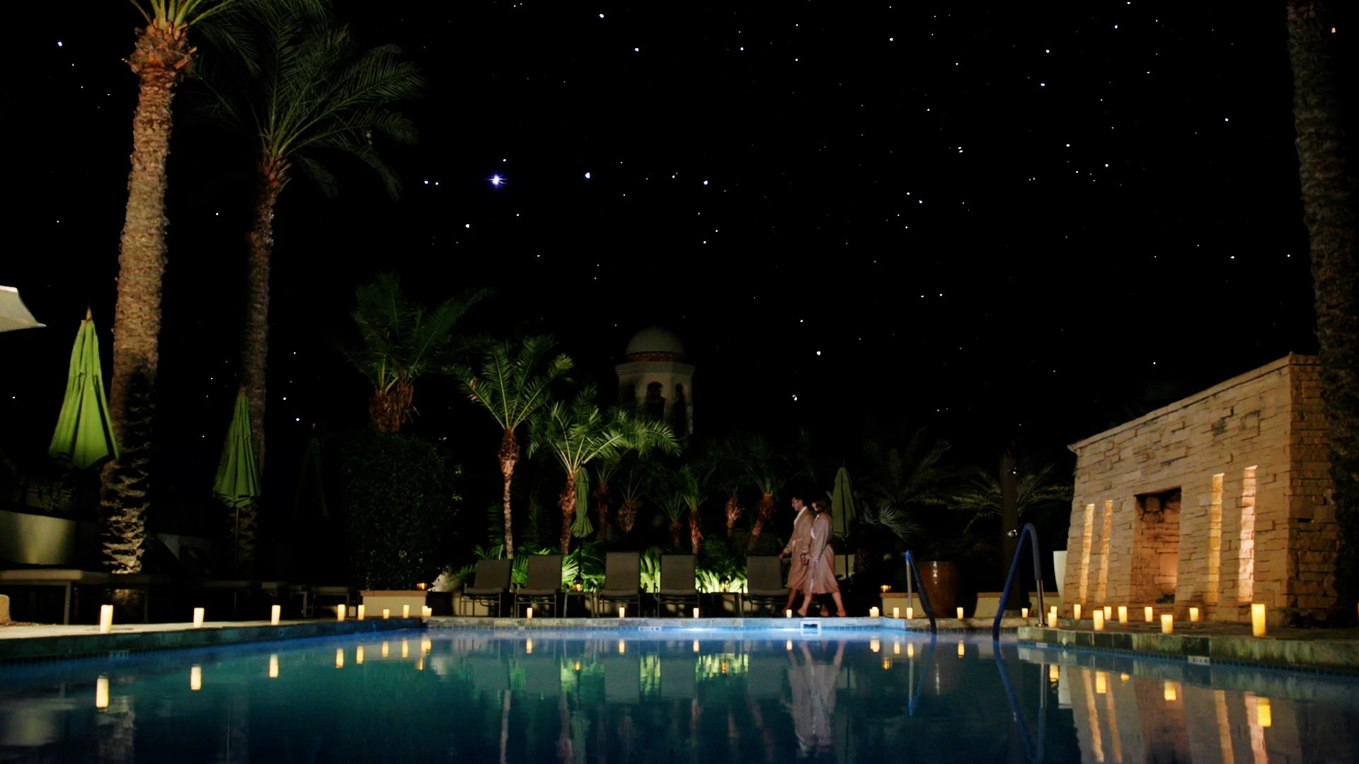 a couple walking in a pool at night