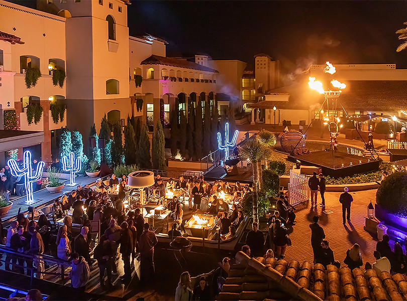 a group of people outside a building with a fire pit