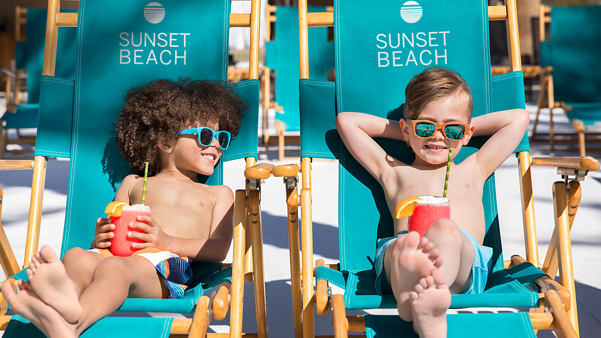 two children sitting in pool lounge chairs