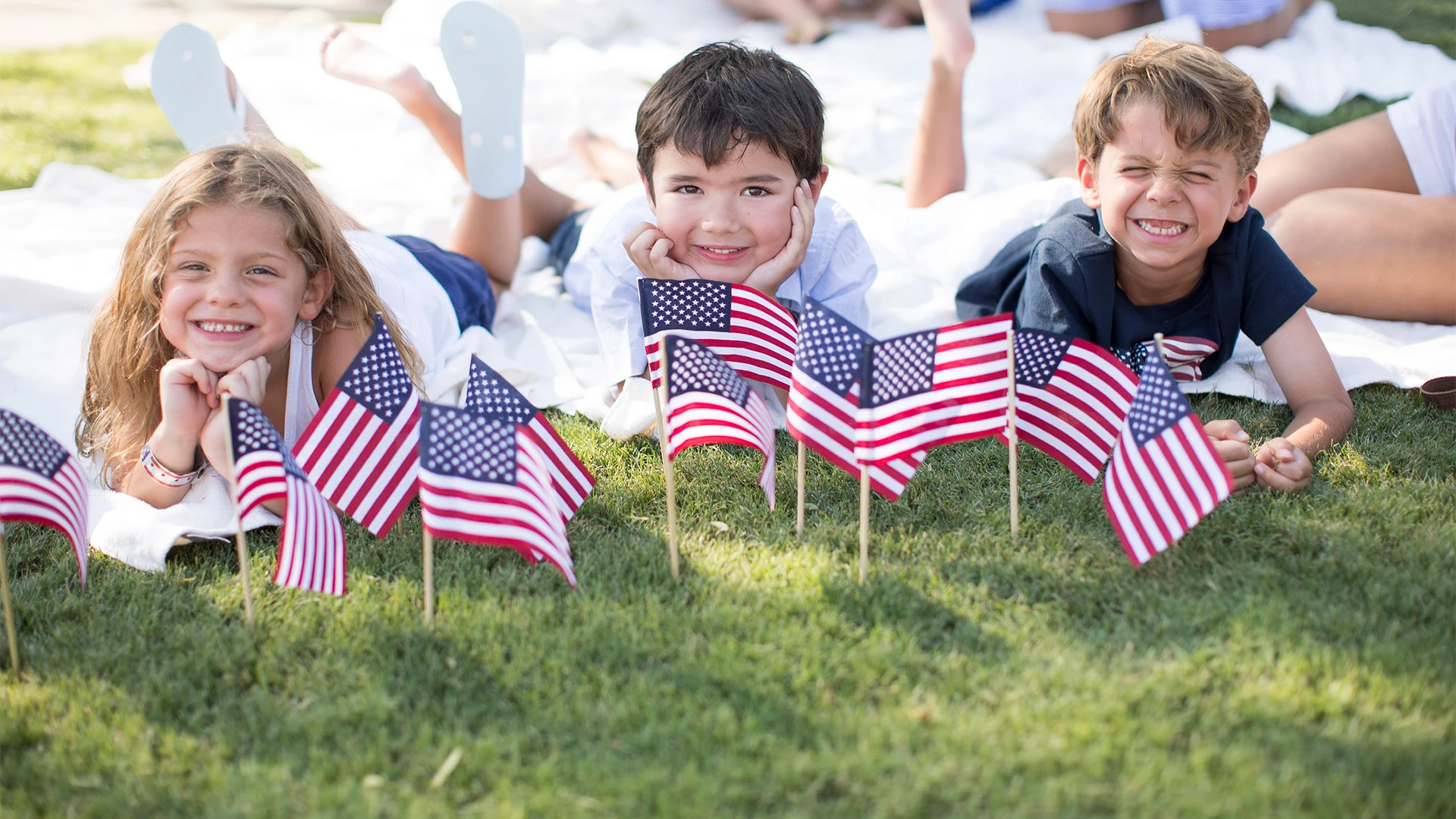 a group of kids lying on the grass with small flags