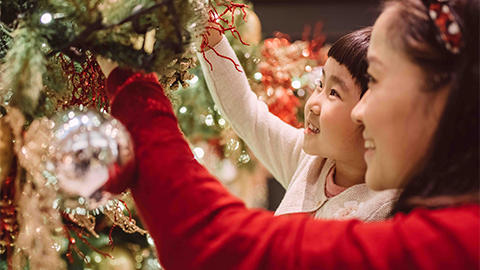a person and a girl looking at a christmas tree