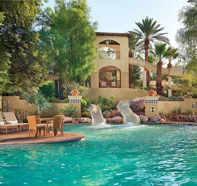 a pool with chairs and a building in the background