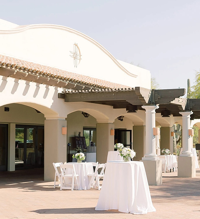 a white table with white cloths and tables with white tables and chairs outside of a building