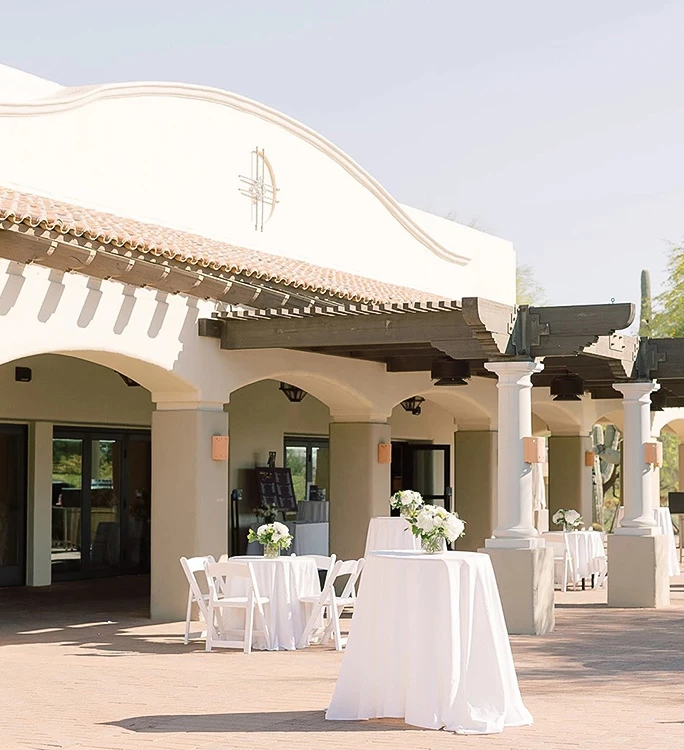 a white table with white cloths and tables with white tables and chairs outside of a building