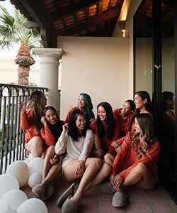 a group of girls sitting on a balcony while looking and smiling at each other