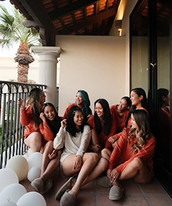 a group of girls sitting on a balcony while looking and smiling at each other