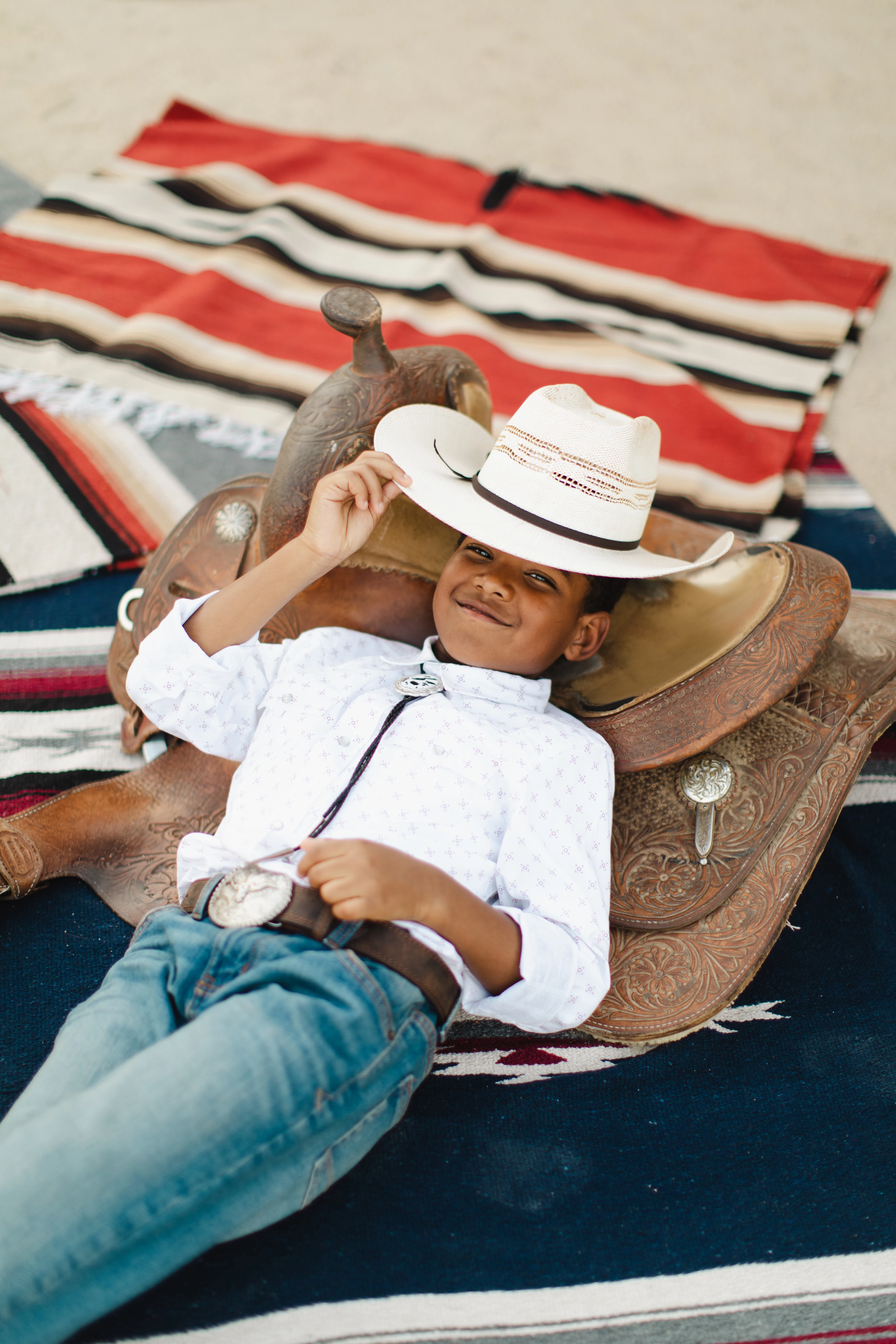a boy lying on a blanket with a cowboy hat