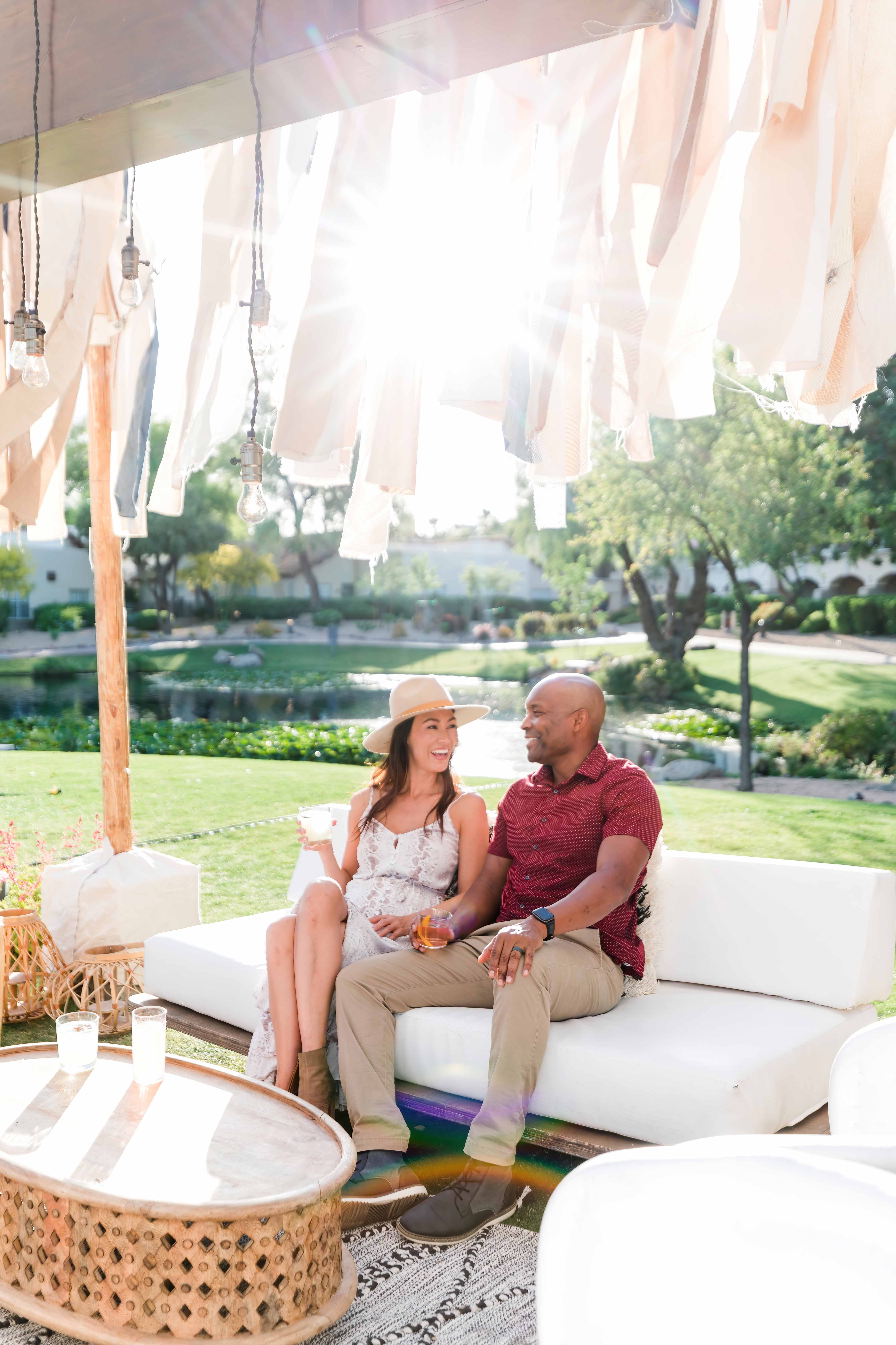 a man and woman sitting on a couch under a white tent