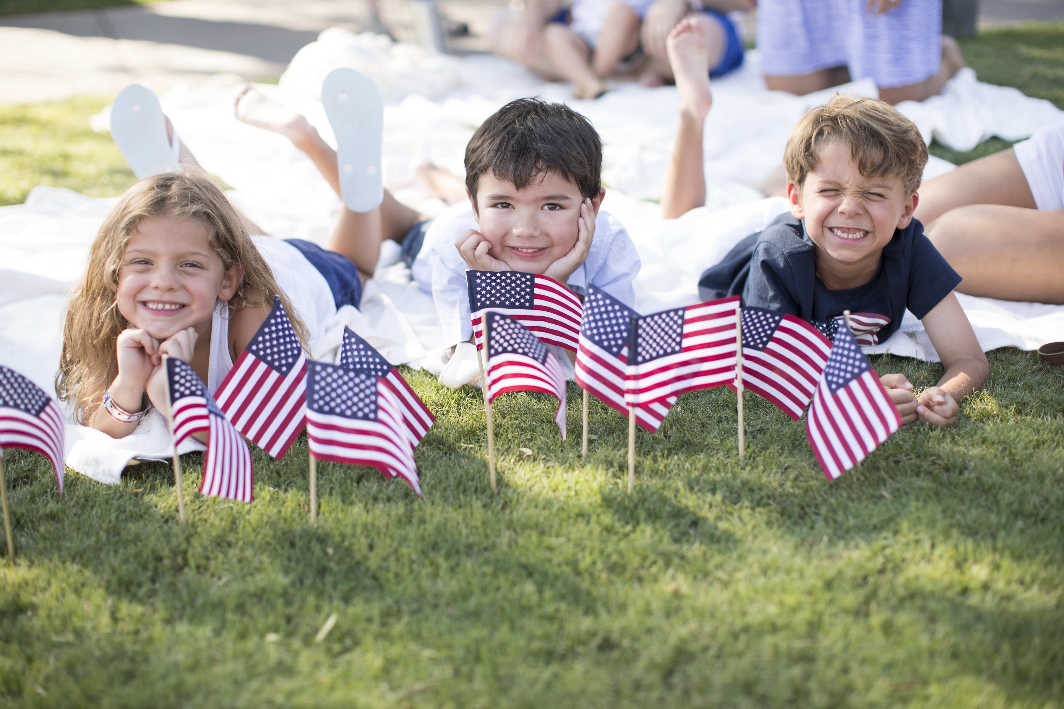a group of children lying on the grass with small flags