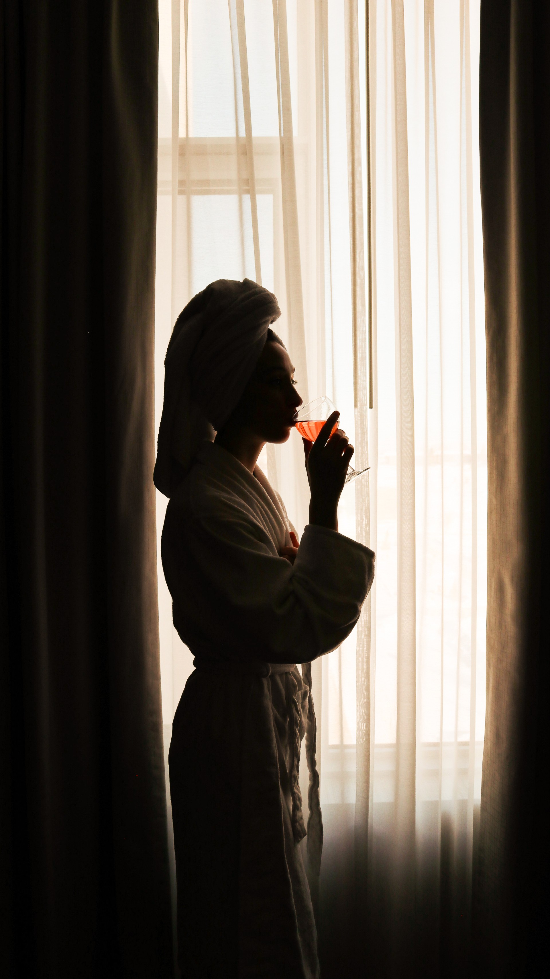 a woman in a bathrobe drinking from a glass