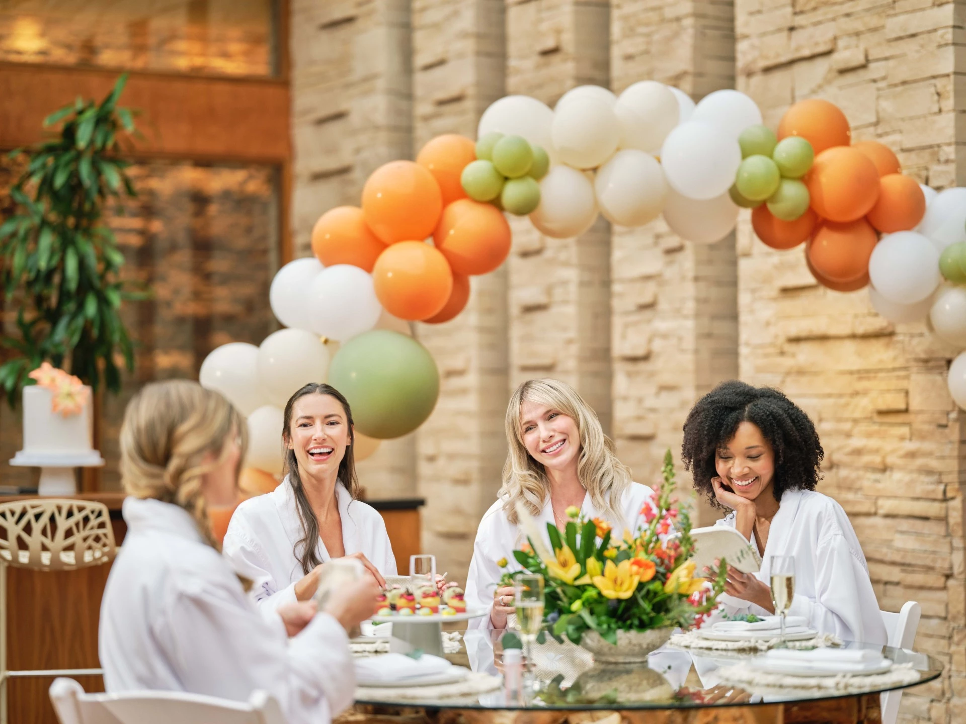 a group of women sitting at a table with balloons