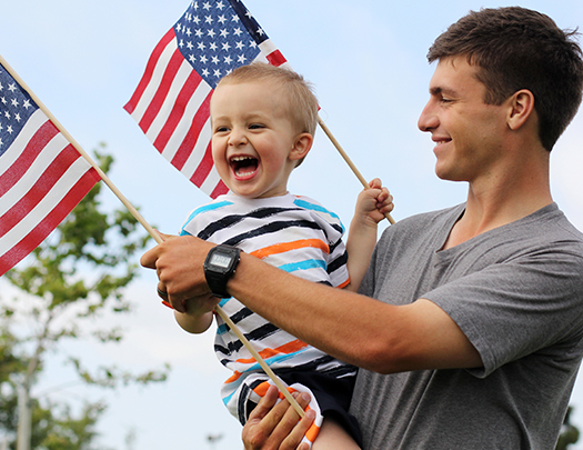 a man holding a child and holding flags