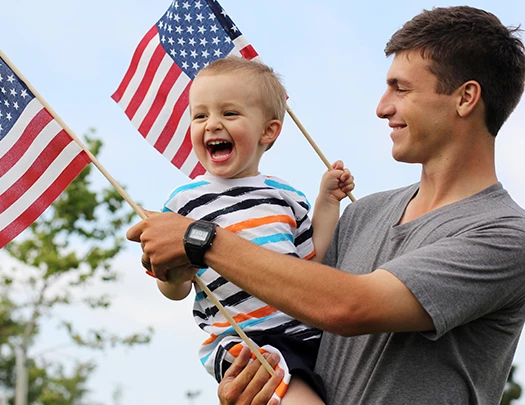 a man holding a child and holding flags