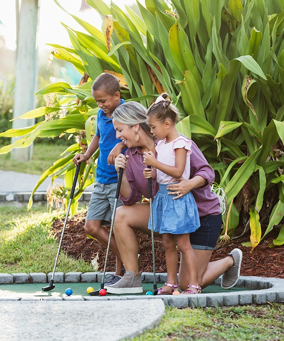 a woman and kids playing mini golf