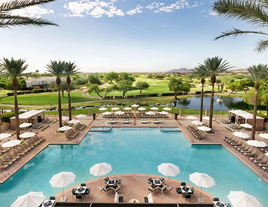 a pool with umbrellas and chairs and a golf course
