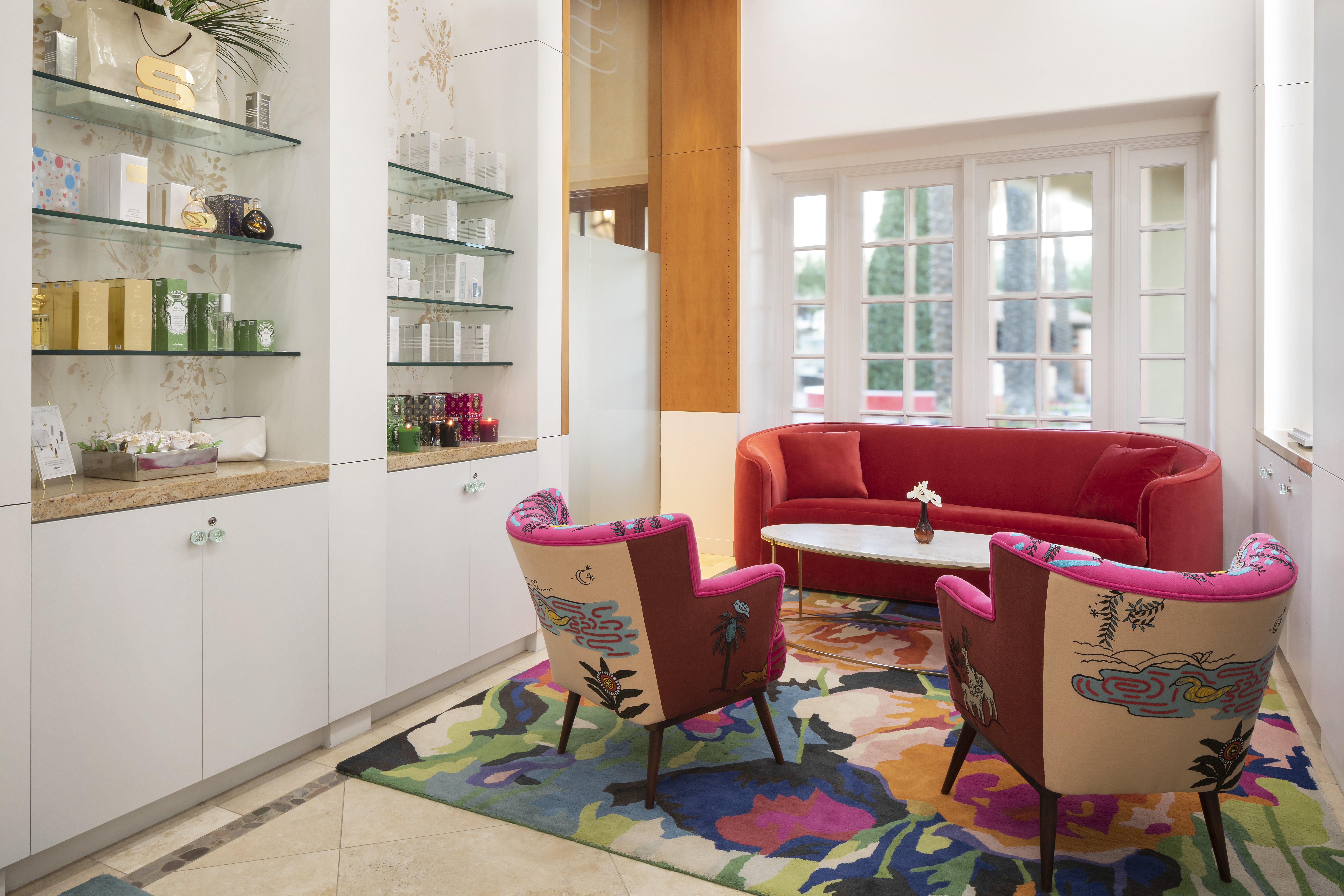 a seating area with bright colored couch and chairs with spa products on the wall to the left