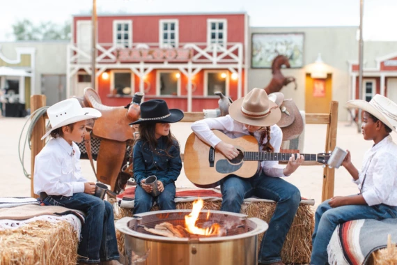 a group of people sitting on hay bales playing guitar and sitting on hay bales