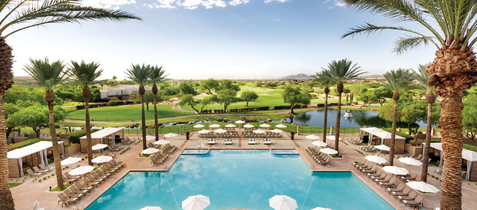 a pool with umbrellas and chairs and a golf course