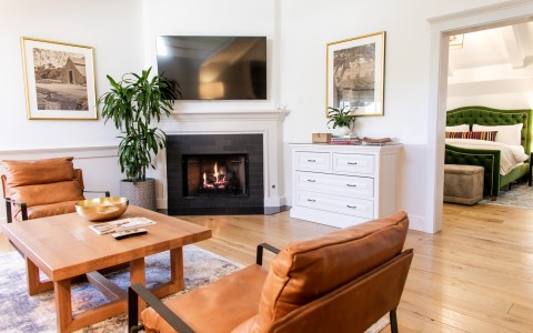 Sitting area with TV and fireplace of the Marcella Suite at Fess Parker Wine Country Inn with bedroom in background