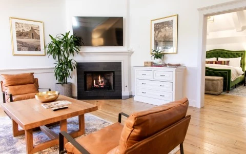 Sitting area with TV and fireplace of the Marcella Suite at Fess Parker Wine Country Inn with bedroom in background