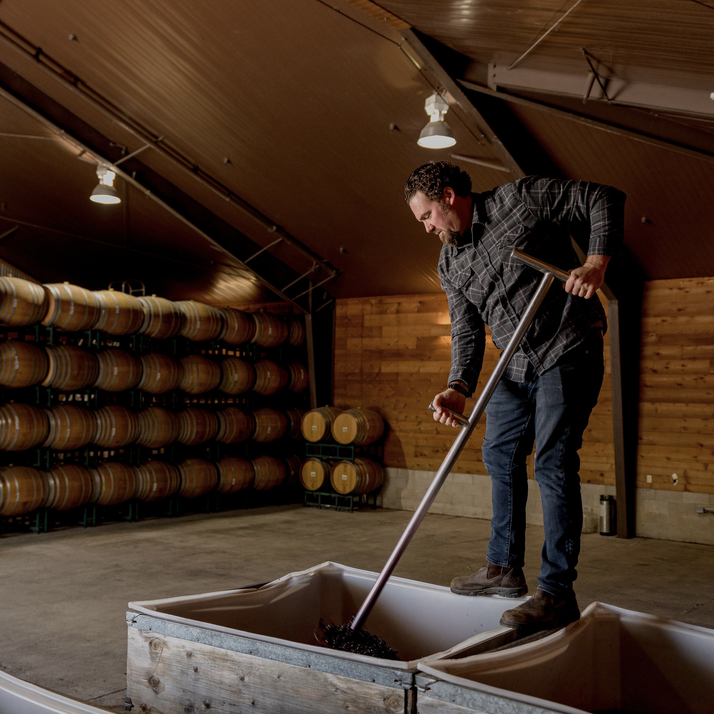 a man holding a shovel in a room with barrels