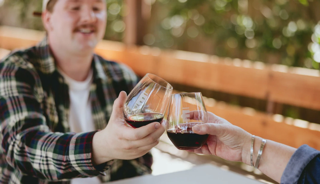 Two people clinking glasses of Epiphany red wine at Epiphany tasting room in Los Olivos, CA