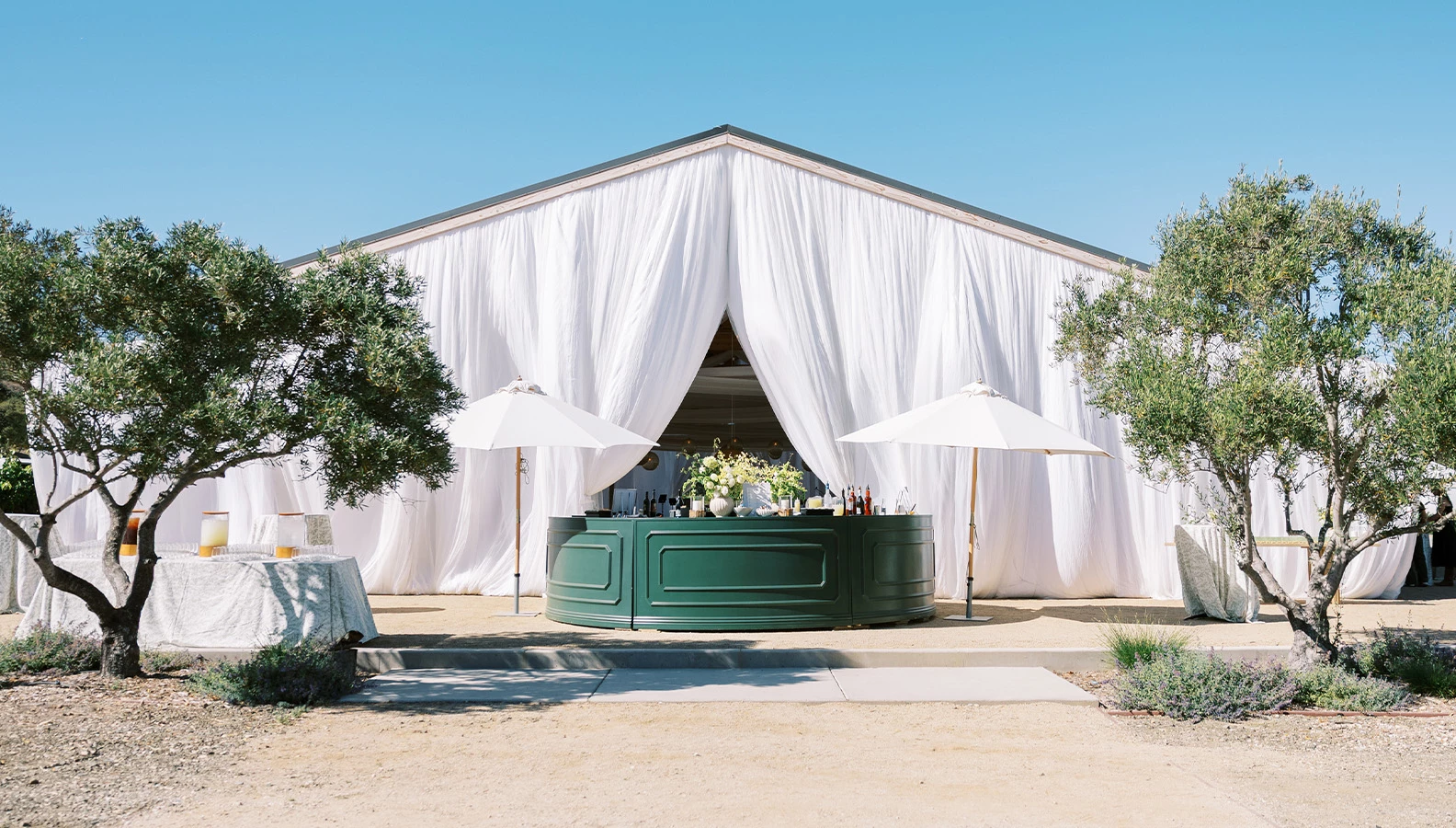a white tent with a table and umbrellas