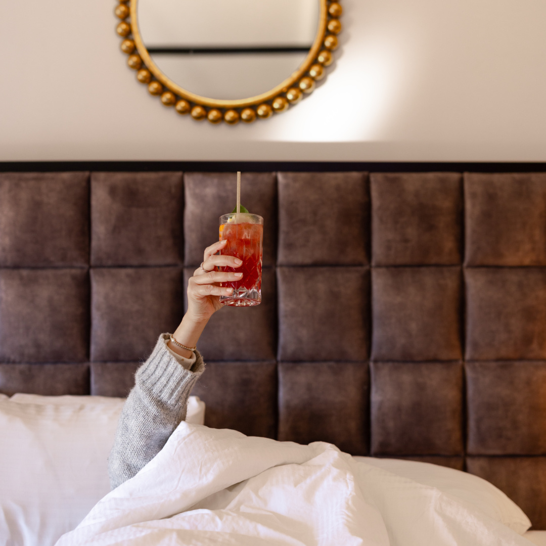 Guest holding a cocktail while in bed at Fess Parker Wine Country Inn in Los Olivos, CA