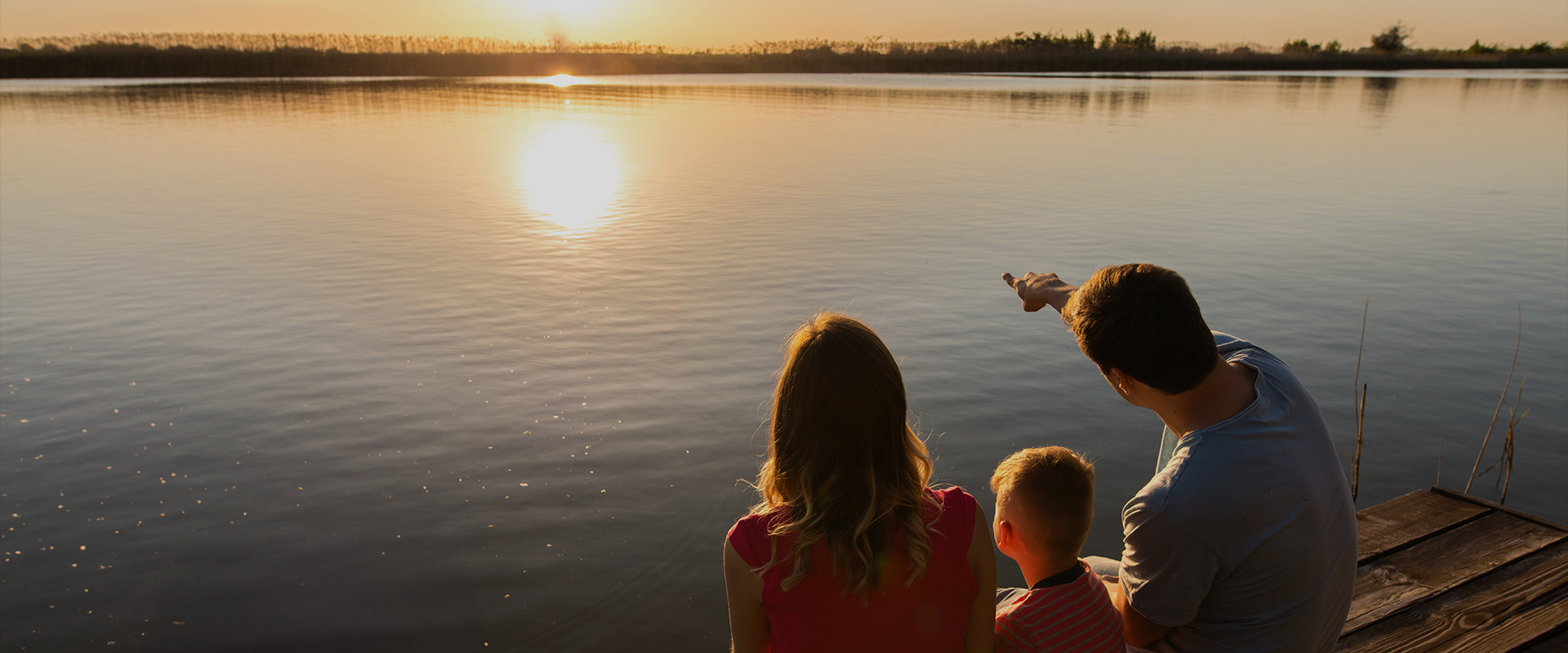 a group of people sitting on a dock looking at the sun