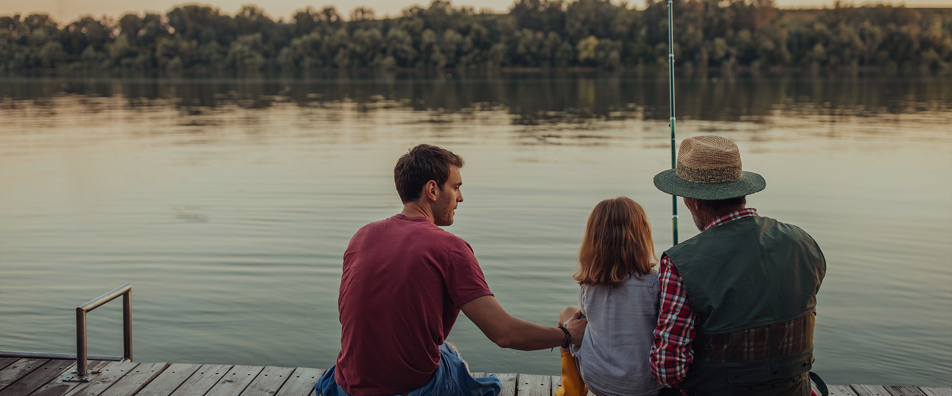 a man and girl sitting on a dock looking at a lake