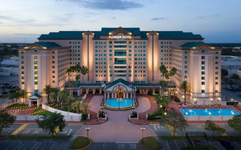 a large hotel with a pool and palm trees