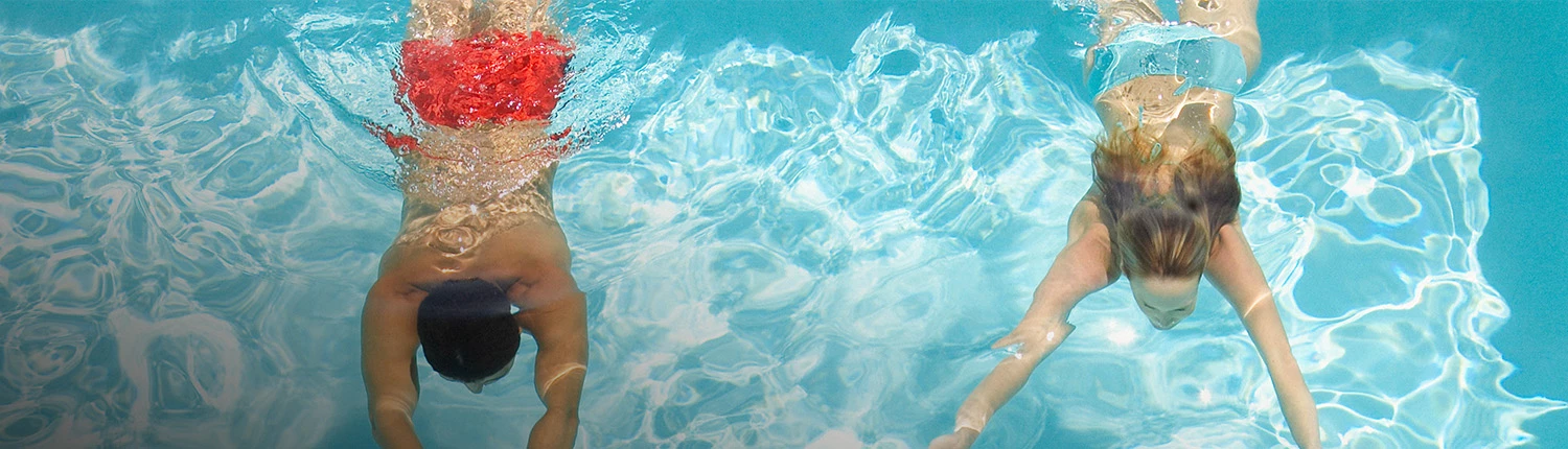 two people swimming underwater in pool