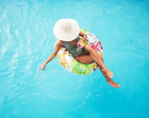 a woman in a swimsuit and hat on a float in a pool