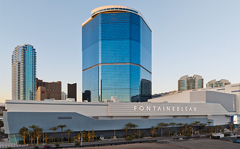 a large blue building with a white wall and palm trees