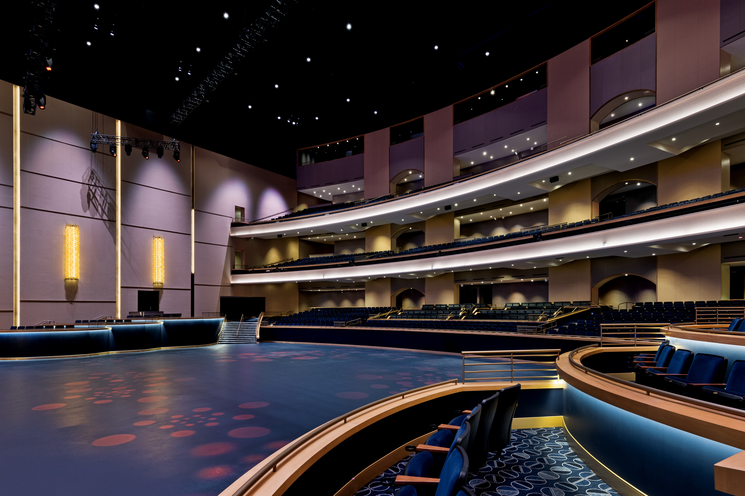 a large auditorium with blue seats and a round stage