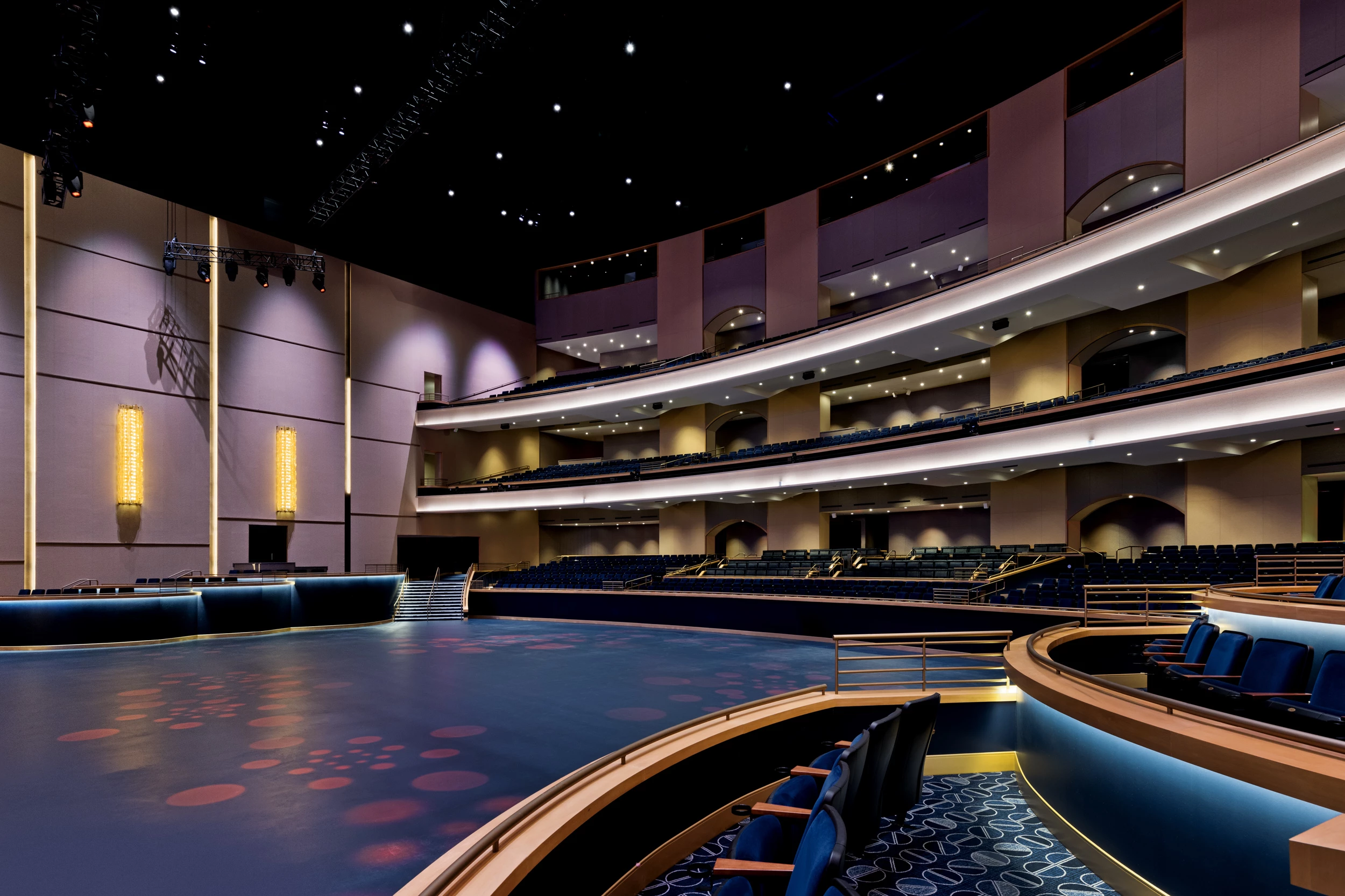a large auditorium with blue seats and a round stage